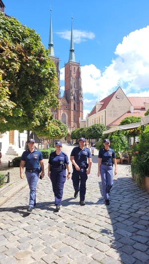 Czwórka umundurowanych policjantów, dwójka włoskich, dwójka polskich idzie ulicą miasta