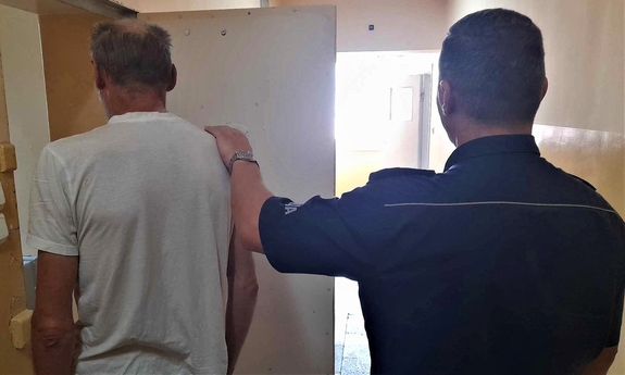 policjanci prowadzą zatrzymanego mężczyznę