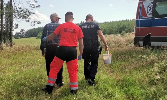 policjant i ratownik medyczny wyprowadzają z lasu odnalezionego mężczyznę