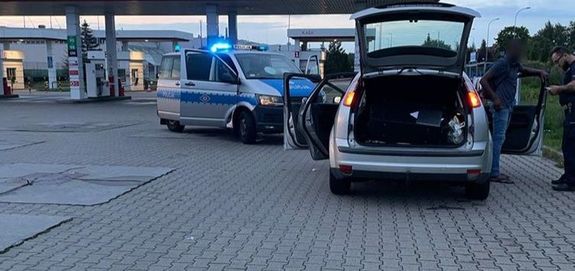 umundurowany policjant z zatrzymanym mężczyzną