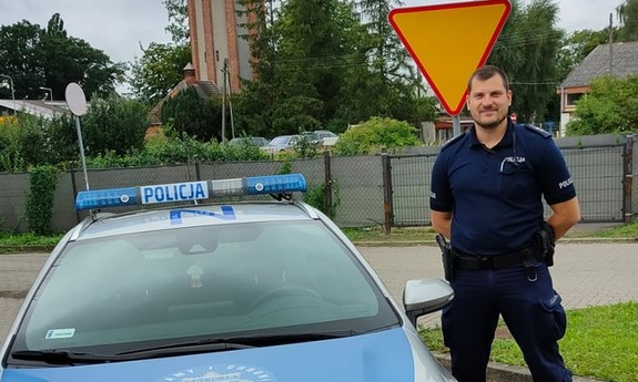 Policjant stoi przy radiowozie policyjnym