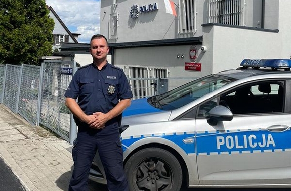 umundurowany policjant stoi przy radiowozie