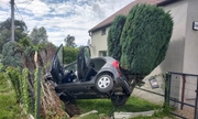 Na zdjęciu widoczny samochód osobowy, który wypadł z drogi i zawisł na ogrodzeniu posesji