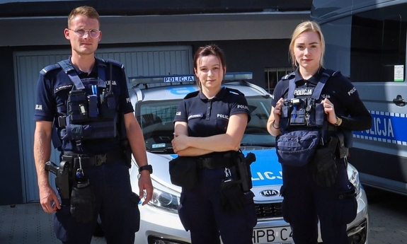 Dwie policjantki i policjant stojący przy radiowozie