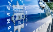 srebrne logo policji na niebieskich drzwiach oznakowanego radiowozu