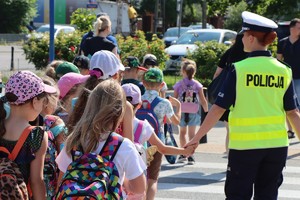 Policjantka prowadząca grupę dzieci w wieku szkolnym.