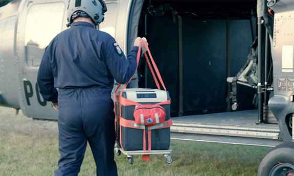 Pilot niesie pojemnik do transportu organów w kierunku oczekującego śmigłowca.