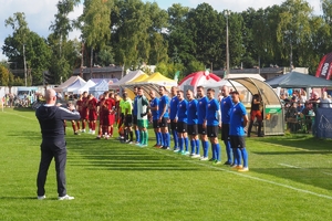 dwie drużyny w niebieskich i czerwonych koszulkach przed meczem
