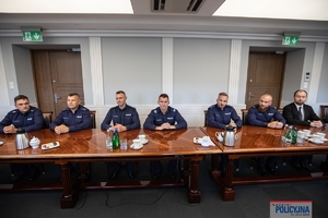 Policjanci siedzą przy stole na sali Generalskiej