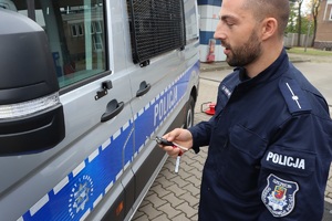 Policjant trzyma w ręku kluczyki do nowego radiowozu i idzie go otworzyć