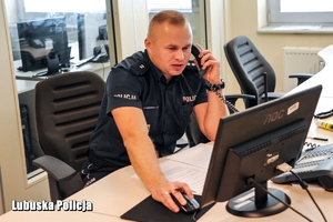 policjant siedzi przy biurku i rozmawia przez telefon służbowy