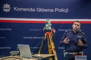 policjant stojący na tle rollupu z napisem Komenda Główna Policji