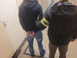 policjant z zatrzymanym zakutym w kajdanki z tyłu