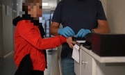 policjant pobiera odciski palców od zatrzymanej kobiety
