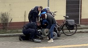 Zdjęcie z monitoringu. Policjanci pomagają mężczyźnie, któremu uszkodziło się koło przy wózku inwalidzkim