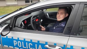 Za kierownicą radiowozu siedzi umundurowany policjant