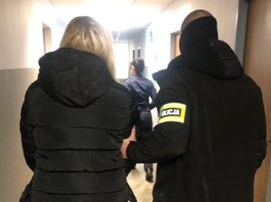 zatrzymana kobieta prowadzona korytarzem przez policjanta