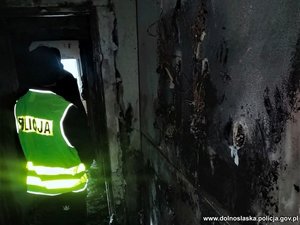 Policjant w odblaskowej kamizelce w spalonym budynku