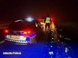 Policjant stojący przy radiowozie na drodze w porze nocnej