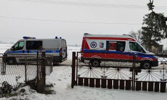 karetka pogotowia i radiowóz policyjny stoją przed bramą posesji