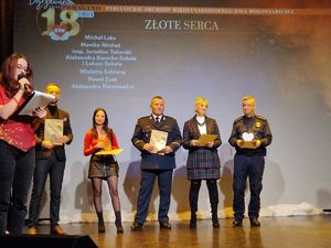 Komendant Powiatowy Policji w Pabianicach stoi na scenie pośród innych laureatów nagrody Złotego Serca