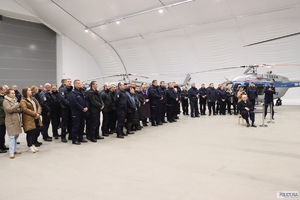 Policjanci i inni goście konferencji w hangarze, w tle śmigłowiec