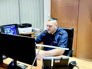 umundurowany policjant siedzi przed monitorem