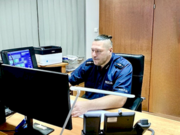 umundurowany policjant siedzi przed monitorem komputera