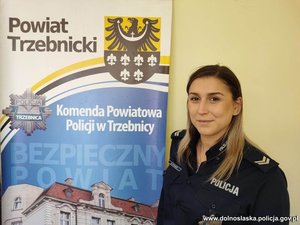 Policjantka stoi koło tablicy z informacją KPP w Trzebnicy