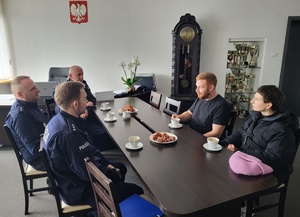 policjanci z obywatelem Niemiec siedzą przy stole i rozmawiają
