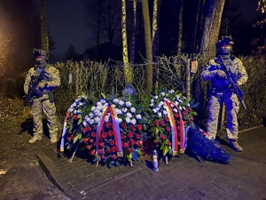 Dwaj funkcjonariusze przy pomniku upamiętniającym policjantów CPKP BOA poległych podczas akcji, pod pomnikiem złożone wieńce