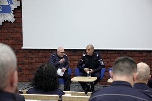 Pełnomocnik KGP ds. Ochrony Prawa Człowieka i  zastępca Komendanta Głównego Policji siedzą przy stoliku na fotelach ustawionych na scenie w trakcie trwania forum