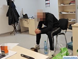 Zatrzymany mężczyzna w kajdankach na rękach siedzi na krześle w pokoju przesłuchań
