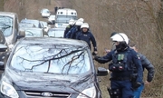 funkcjonariusze Policji podczas akcji na drodze leśnej obok stojących samochodów