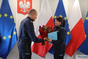 Zastępca komendanta głównego Policji gratuluje policjantce wręczając bukiet kwiatów