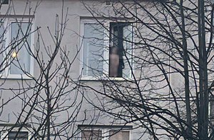 Na zdjęciu dziecko stoi na parapecie i wychyla się przez okno