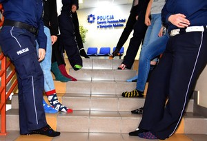 policjanci i pracownicy stoją na schodach mając różne skarpetki