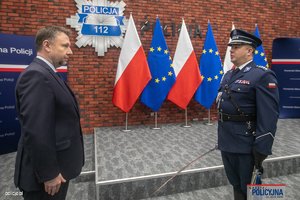 minister swia i policjant. w tle flagi Polski i UE