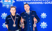 policjant i policjantka z medalami w dłoniach