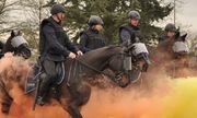 policjanci siedzą na koniach. wokół nich dym pomarańczowo-żółty