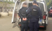 policjanci prowadzą zatrzymanego mężczyznę do radiowozu