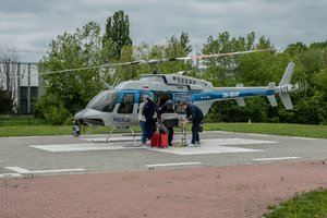 śmigłowiec na lądowisku, obok niego grupa ludzi