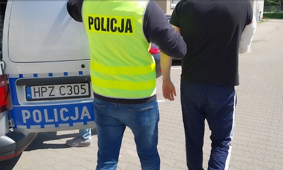 policjant prowadzi zatrzymanego mężczyznę