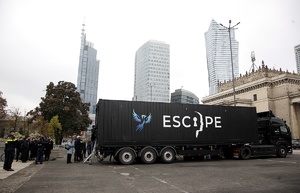 Escape van, przed którym gromadzą się ludzie. W tle miasto i zabudowania