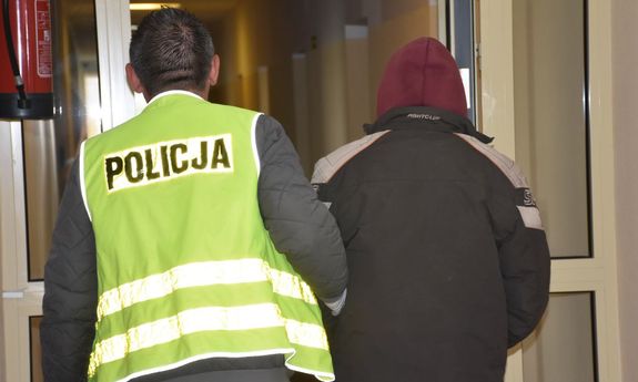 policjant prowadzi zatrzymanego
