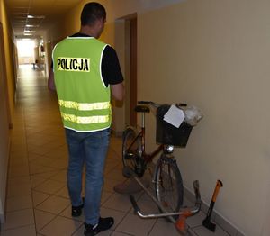policjant stoi przy odzyskanym rowerze i kosiarce spalinowej