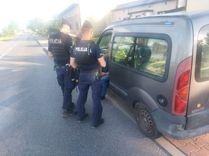 umundurowani policjanci stoją przy zatrzymanym samochodzie