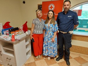 policjant na zdjęciu przy stoisku krwiodawstwa z personelem PCK oddział Krosno
