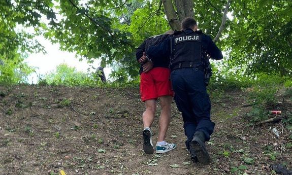 las. policjant idzie z zatrzymanym