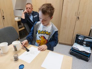 chłopiec maluje pędzelkiem po kartce zbierając odciski